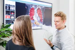 Ein Pneumologe des LungenZentrums Hirslanden Zürich deutet im ILD-Board bei einer Fachbesprechung auf eine radiologische Lungenaufnahme