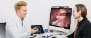 Ein Pneumologe erklärt einer Patientin ein thorakoskopisches Bild einer Lungenoperation am Bildschirm