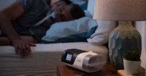 Ein Mann schläft im Bett und trägt eine CPAP-Maske zur Behandlung von Schlafapnoe im Rahmen der Schlafmedizin
