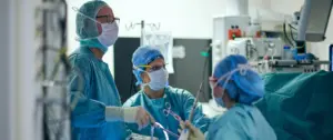 Drei Thoraxchirurgen des LungenZentrums Hirslanden Zürich blicken während einer Operation fokussiert auf die OP-Monitore